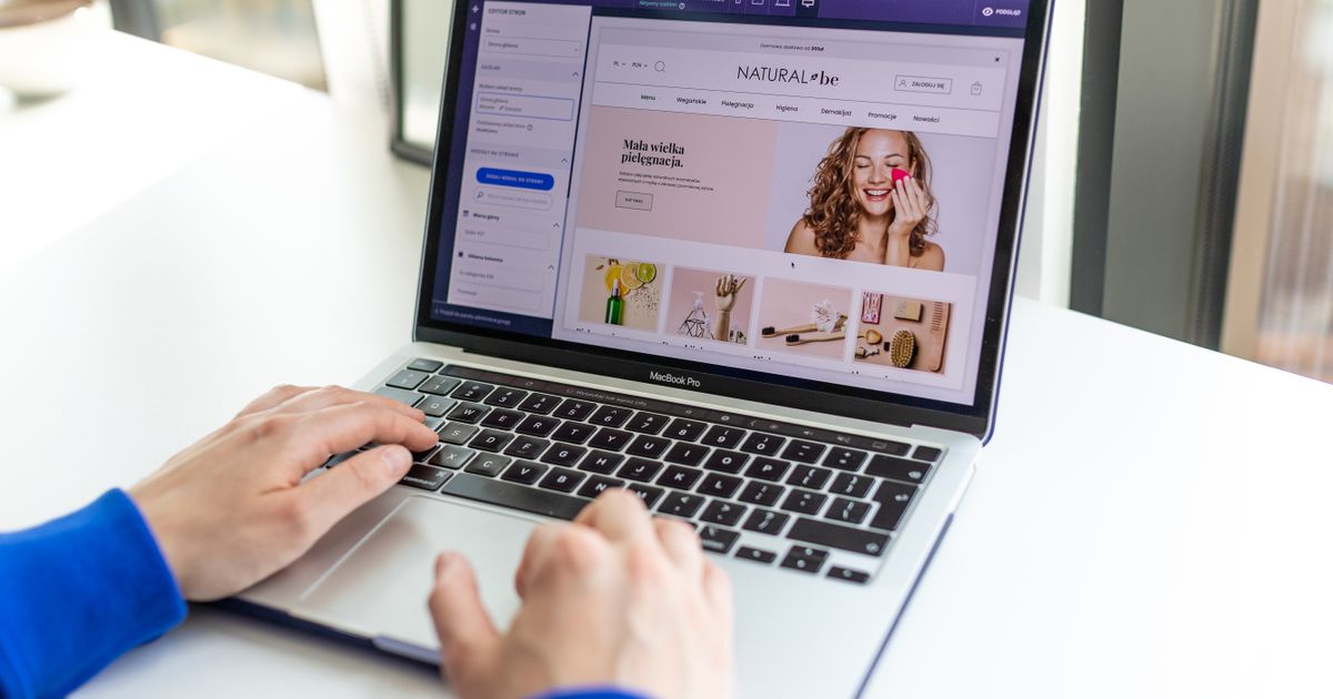Hands typing on a laptop showing an online store page at a white desk