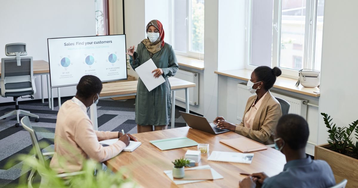 A woman presenting a chart to colleagues seated around a meeting table