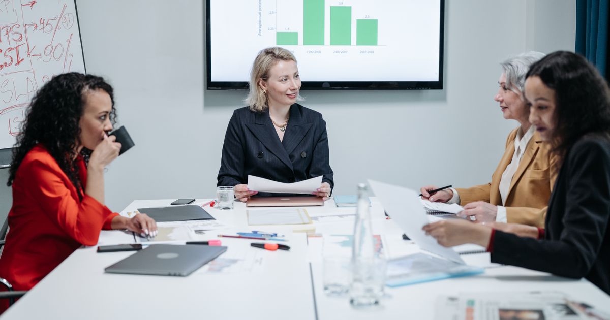 Team meeting at a conference table with a bar chart on the screen behind them